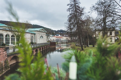 Buildings by river against sky