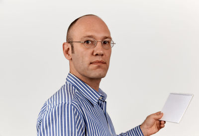 Mid adult man holding eyeglasses against white background