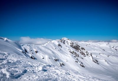 Scenic view of snowcapped mountains against clear blue sky