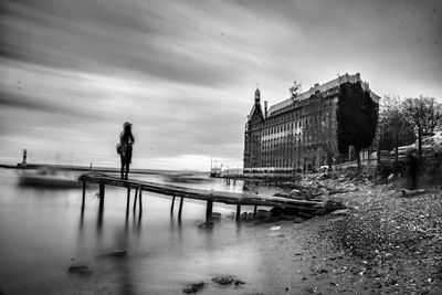 Man on bridge over river against sky