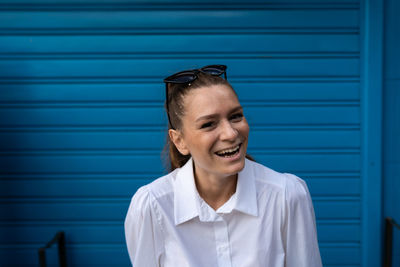 Portrait of smiling young woman against blue wall