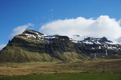 Panoramic view of field and mountains against sky