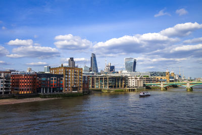 View of buildings by river against cloudy sky