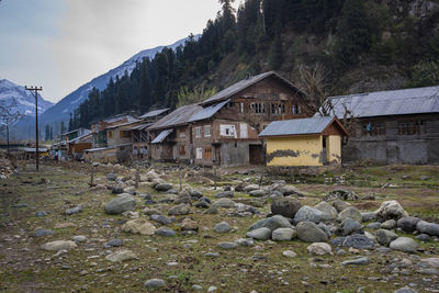 Houses by rocks on shore against sky