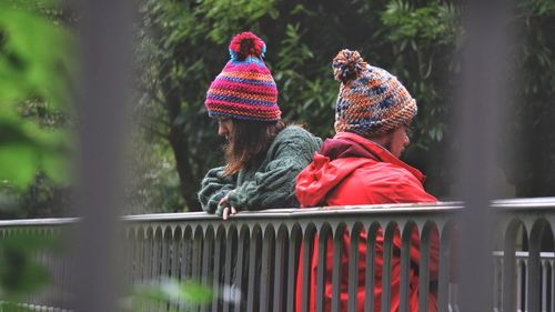 Friends wearing knit hats by railing at park