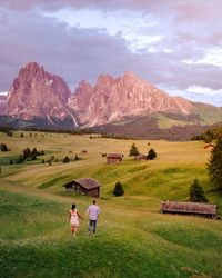 Rear view of couple on field by mountains against sky