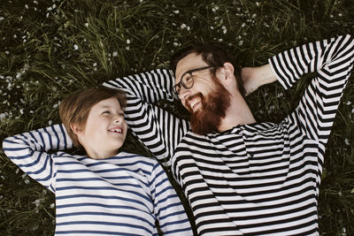 Father and son wearing similar stripped shirts lying on grass