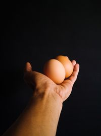 Close-up of hand holding apple against black background