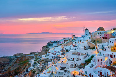 High angle view of townscape by sea against sky during sunset