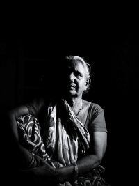 Mid adult man sitting against black background