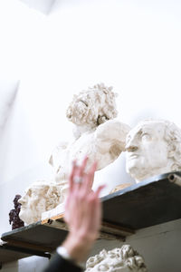 Close-up of woman hand against sculpture
