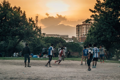 People playing in playground against sky during sunset
