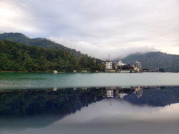 Reflection of buildings and trees in water against sky