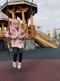 Full length portrait of smiling girl standing against bridge
