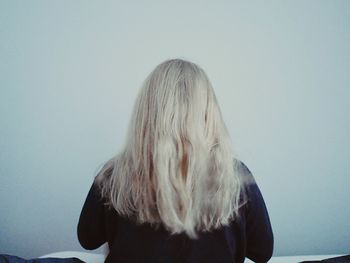 Rear view of woman with blond hair against wall