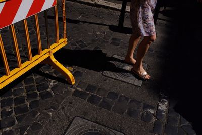 Low section of woman standing on street against barricade