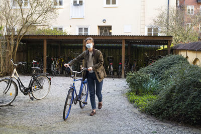 Woman with bicycle wearing face mask