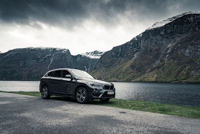 Car on road by mountains against sky