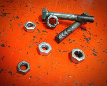 High angle view of nuts and bolts on orange table