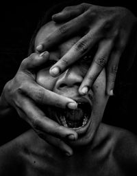 Close-up of hands holding baby hand over black background