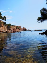 Rock formations in sea against blue sky