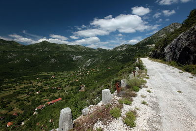 Empty road leading towards mountains against sky