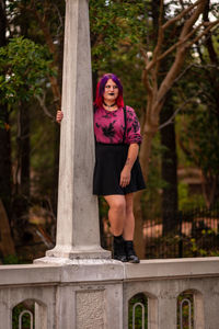 Front view of woman standing against street light post