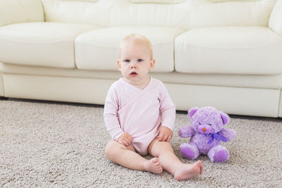 Cute baby girl sitting with toy at home