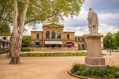 Statue by historic building against sky