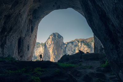 Silhouette man standing in cave against sky