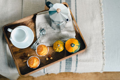 Morning coffee with pumpkin muffins on a wooden tray.