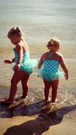 Sisters wearing swimwear while standing on shore at beach