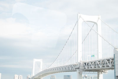 Suspension bridge in city against sky