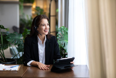 Young woman using phone while sitting on table