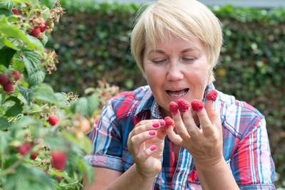 A woman put raspberries on her fingers and shows her original berry manicure