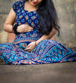 Young pregnant women showing her round belly womb with hand from different angle