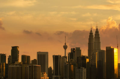 Modern buildings in city against sky during sunset