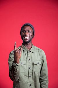 Portrait of smiling young man against red background