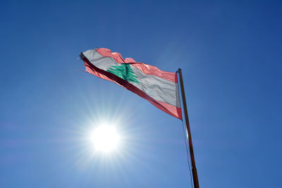 Low angle view of lebanese flag against blue sky