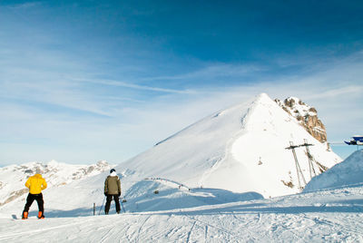 Rear view of people on snow covered mountain against sky