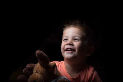 Close-up of cute boy with toy against black background