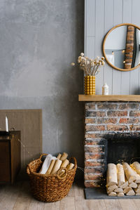 Scandinavian interior with red brick fireplace, wicker basket for firewood, pile of logs for a fire