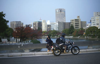 People riding motorcycle on road against cityscape