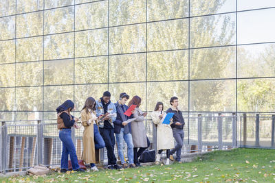 Multiracial friends studying by college building