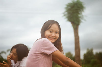 Portrait of smiling girl against plants and trees against sky