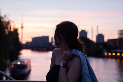 Woman standing against river during sunset