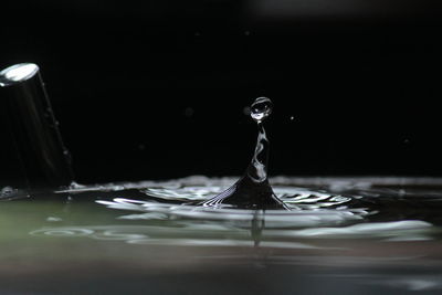 Close-up of drop falling in container at night