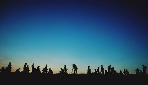 Silhouette people on field against clear sky during sunset