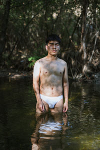 Portrait of shirtless man standing in lake