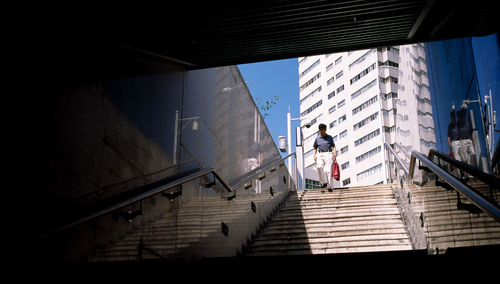 Low angle view of staircase by buildings in city against sky